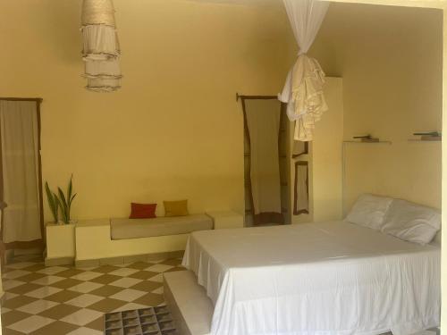 a bedroom with a white bed and a checkered floor at Takasira Appart Hôtel Downtown in Fort Dauphin