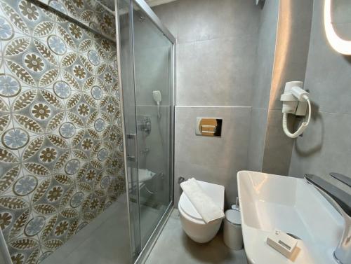 a bathroom with a shower and a toilet and a sink at Alicante Otel - Adult Only in Bozcaada