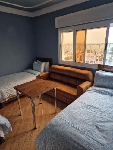 a room with two beds and a couch and a table at NOUARA Appart'hotel in Chefchaouen