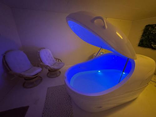 a bathroom with a blue tub and two chairs at Tjeldøya Slott in Hov