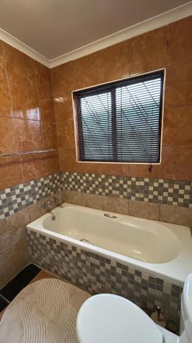 a bathroom with a tub and a toilet and a window at TinasRose in Uvongo Beach