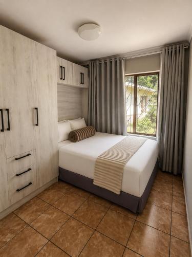 a bedroom with a bed and a window at TinasRose in Uvongo Beach