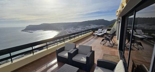 a balcony with chairs and a view of the ocean at Apartment with a stunning view over Sesimbra in Sesimbra