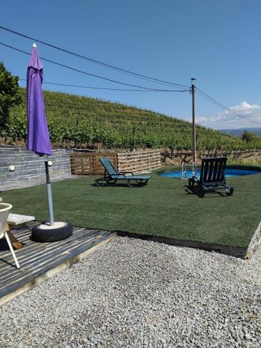 a patio with two chairs and an umbrella at Retiro da Quinta do Souto in Peso da Régua