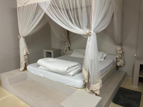 a bedroom with a bed with white drapes at Takasira Appartment Downtown 2 in Fort Dauphin