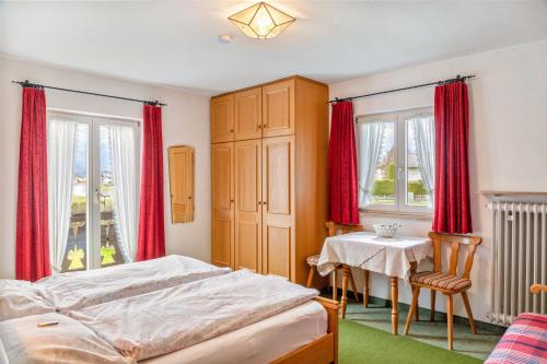 a bedroom with red curtains and a bed and a table at Ferienwohnung 1 in Wallgau