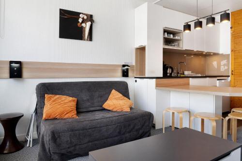 a living room with a couch and a kitchen at Studio Moderne Pied Des Pistes 4 p in La Pierre Saint Martin