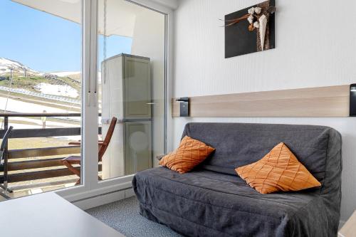 a gray couch with two orange pillows in a room at Studio Moderne Pied Des Pistes 4 p in La Pierre Saint Martin