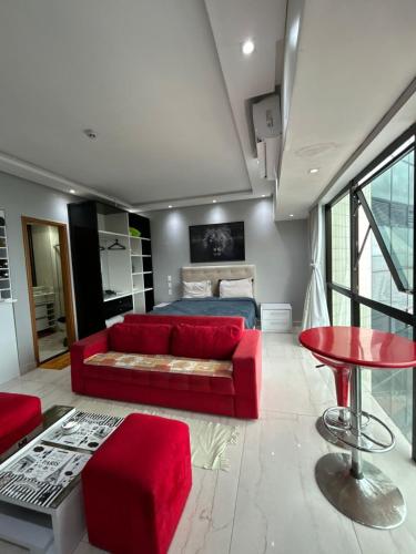 a bedroom with a red couch and a bed at Tropical Executive Vista Pôr do Sol in Manaus