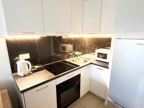 a kitchen with white cabinets and a stove top oven at Apartament Gozo in Łódź