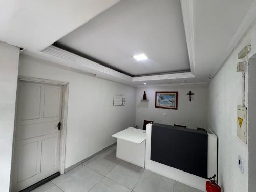 a white room with a tv and a door at Hotel Avenida ao lado do shopping in Guaratinguetá