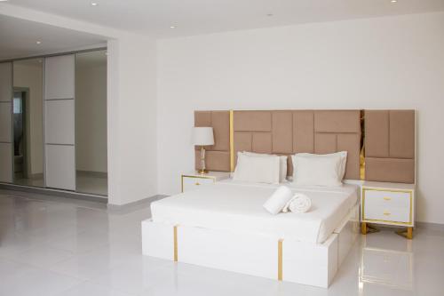 a white bedroom with a large white bed and a mirror at Hotel Kilimanjaro in Luanda