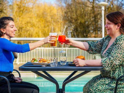 a man and woman sitting at a table with drinks at Novotel Saint Avold in Saint-Avold