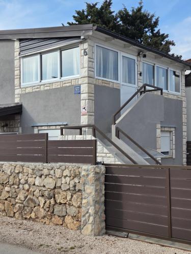 a house with a fence and a stone wall at Apartment Vi & La ELECTRIC SCOOTERS included in Vir