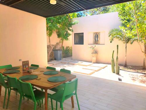 a dining room with a wooden table and green chairs at Villa Lara Palacios, tu oasis en Mérida in Mérida