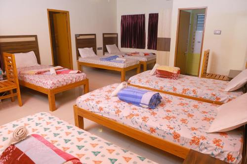a room with four beds and chairs in it at Bhavan Resorts in Yercaud