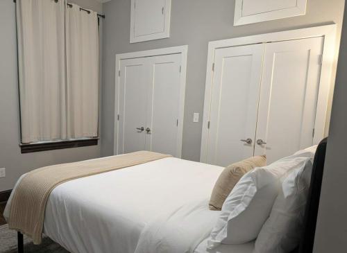 a bedroom with a white bed and two white doors at Modern Downtown Loft Walk to Convention Center in Richmond