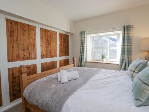 a bedroom with a bed with a wooden headboard and a window at High Ickenthwaite Farmhouse in Ulverston