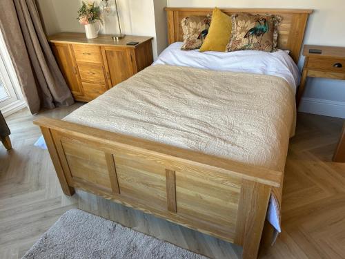 a bed with a wooden frame in a bedroom at Sunny Garden WFH Retreat with Private Entrance and Parking near NEC BHX JLR in Solihull