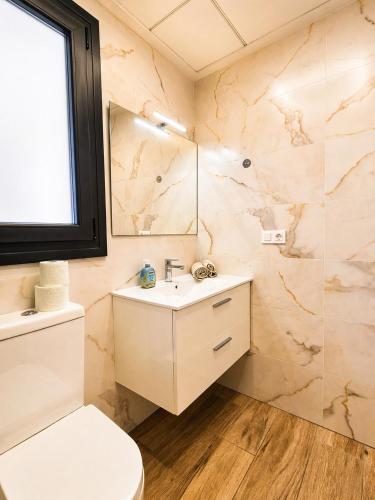 a bathroom with a sink and a toilet and a mirror at Claudia Luxury Apartment near the beach with a pool, gym, and secure gated parking in Arenales del Sol