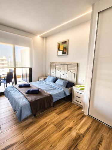 a bedroom with a large bed with a wooden floor at Claudia Luxury Apartment near the beach with a pool, gym, and secure gated parking in Arenales del Sol