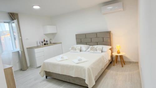 ein weißes Schlafzimmer mit einem Bett, auf dem zwei Handtücher liegen in der Unterkunft Studio Perina in Trogir