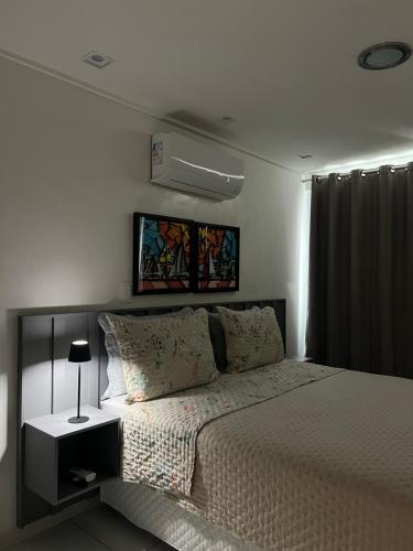 a white bedroom with a bed with a night stand at APART HOTEL MANAIRA PALACe 2 in João Pessoa