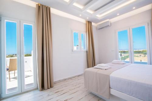 a white bedroom with a bed and a balcony at Depis luxury villas naxos in Plaka