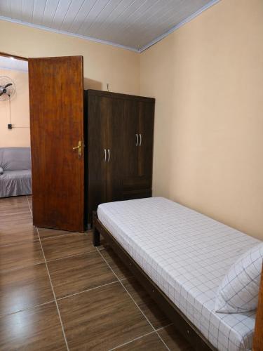 a bedroom with a bed and a wooden cabinet at Hospedagem Horizonte Azul- Recanto São Thomé in Eldorado