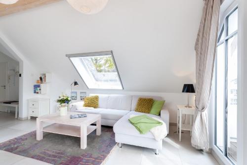 a white living room with a white couch and a window at Am Horizont 2 stilvoll mitten im Herzen von Zingst nahe Seebrücke und Strand Parkplatz und WLAN inklusiv in Zingst