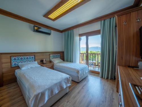 a hotel room with two beds and a balcony at Hotel Azmakhan in Akyaka
