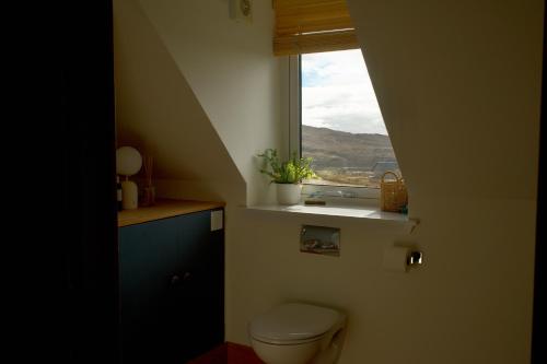 a bathroom with a toilet and a window at Shell Cottage B&B in Toscaig