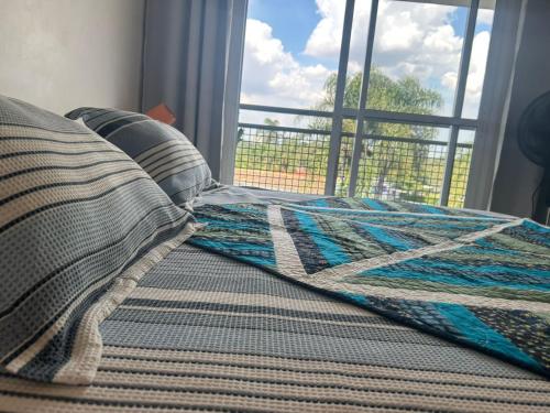 a bed with a blanket on it with a window at Flat Studio Charmoso New Studio Granja Viana Cotia Sao Camillo 642 in Carapicuíba