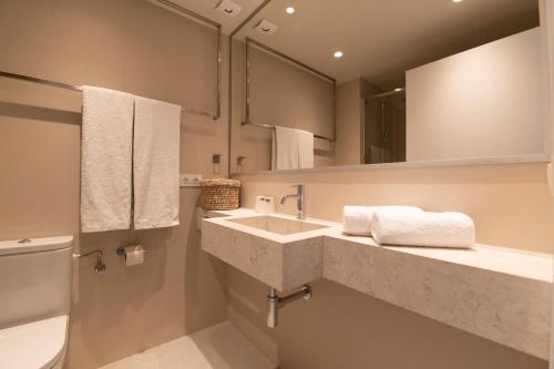 a bathroom with two sinks and a toilet and mirrors at Hotel Roca Plana in L'Ampolla