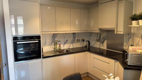a kitchen with white cabinets and a microwave at Malijeed Services limited in London