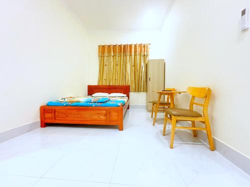 a bedroom with a bed and a table and chairs at HAPPY TEA Motel in Long Hai