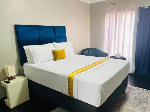 a bedroom with a large bed with a blue headboard at Shiloh Tlokweng in Gaborone
