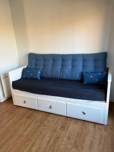 a couch with blue cushions on a white bed at Côte Saint-Pierre in Ambleteuse