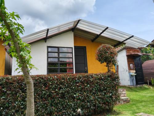 a yellow and white house with a hedge at Bahareque hospedaje in Monguí