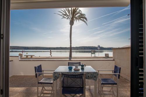 a table and chairs on a balcony with a palm tree at SOL NAIXENT in Fornells