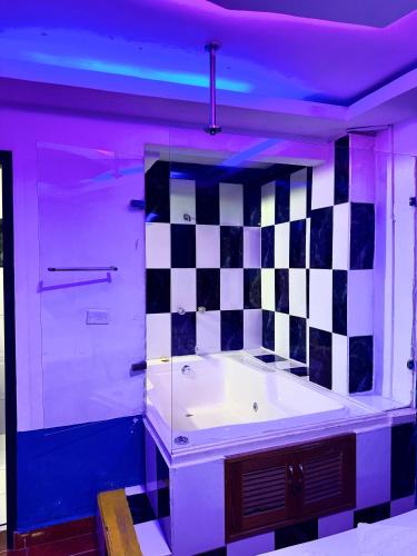 a bathroom with a tub with a checkered wall at Hotel Sol y Luna 1 in Medellín