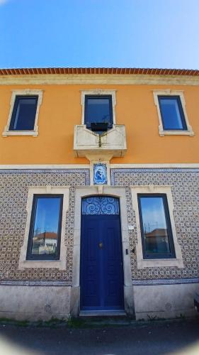 a building with a blue door and windows at Casa de St António in Murtosa