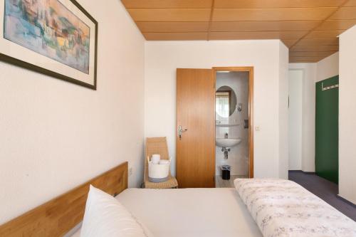 a bedroom with a bed and a bathroom with a sink at Hotel Garni Siedlerstube 2 in Nürtingen