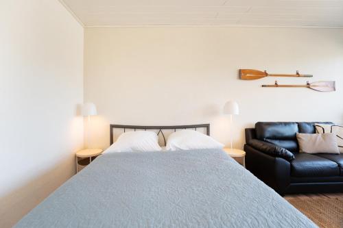a bedroom with a bed and a black leather couch at Strandhaferweg 7 Beach Apartment Fehmarn in Burgtiefe auf Fehmarn 