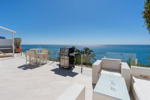 a patio with a grill and a view of the ocean at Maryvilla Inspiración y Vacaciones - Villa Mascarat in Calpe