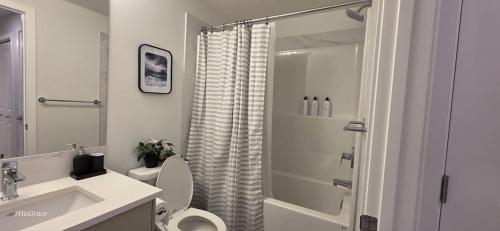 a white bathroom with a toilet and a shower at Cobblebrook Executive Suites in Airdrie