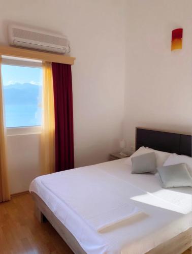 a bedroom with a white bed and a window at Apart hotel Samardzic in Tivat