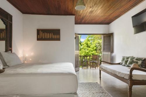 a bedroom with a bed and a couch at Pousada Nativa in Caraíva