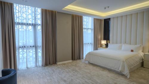 a bedroom with a white bed and large windows at شقق فندقيه رسال in Ar Riyāḑ