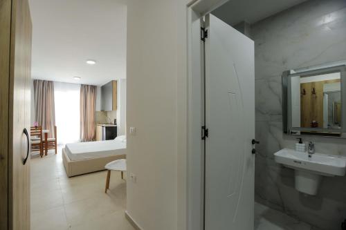 a white bathroom with a sink and a bed at Crown Apartments in Golem